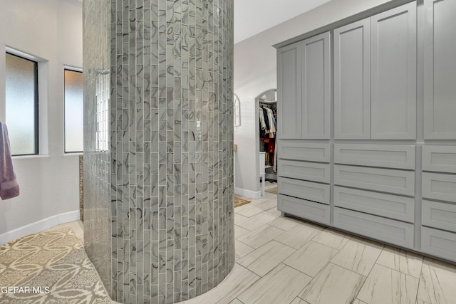 bathroom featuring a walk in shower and baseboards