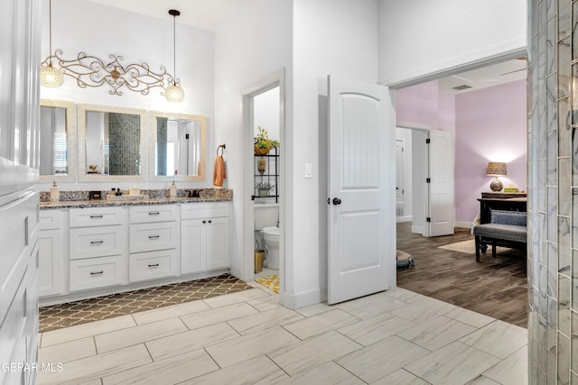 full bathroom featuring double vanity, a towering ceiling, visible vents, and toilet