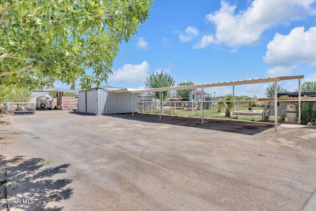 exterior space featuring fence, a storage shed, and a detached carport