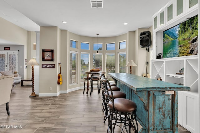 dining space with recessed lighting, visible vents, baseboards, a dry bar, and wood finished floors