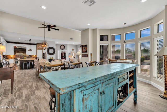 kitchen featuring a wealth of natural light, a kitchen island, white cabinets, ceiling fan, and visible vents