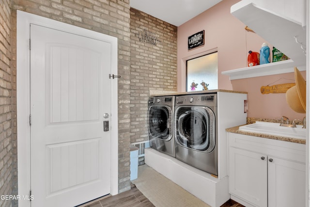 laundry room with brick wall, washing machine and clothes dryer, and a sink