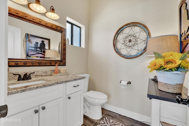 bathroom with toilet, wood tiled floor, vanity, and baseboards