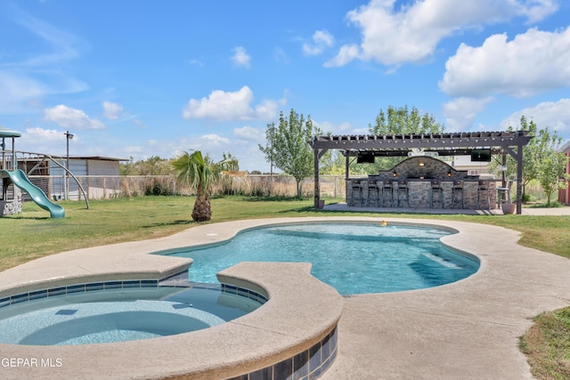 view of pool featuring a fenced backyard, a water slide, outdoor dry bar, a yard, and a pool with connected hot tub