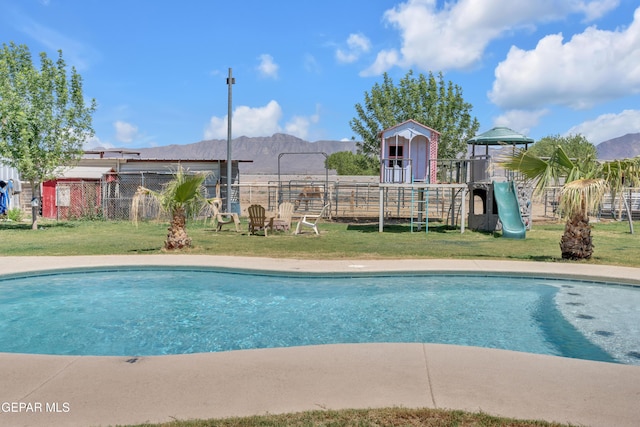 view of swimming pool featuring fence, a yard, playground community, and a fenced in pool