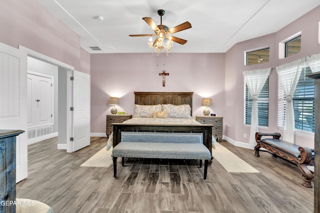bedroom featuring baseboards, visible vents, wood finished floors, and ceiling fan