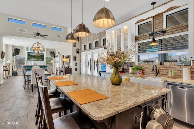 kitchen with a sink, visible vents, decorative light fixtures, white cabinetry, and dishwasher