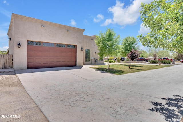 adobe home with a garage, stucco siding, driveway, and a front yard