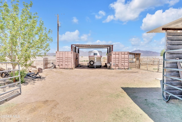 view of yard featuring a mountain view, a carport, and an outbuilding