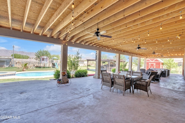 view of patio featuring fence, outdoor dining area, a ceiling fan, and a pool with connected hot tub