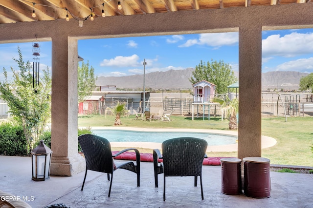 view of patio with a mountain view, a fenced in pool, and fence