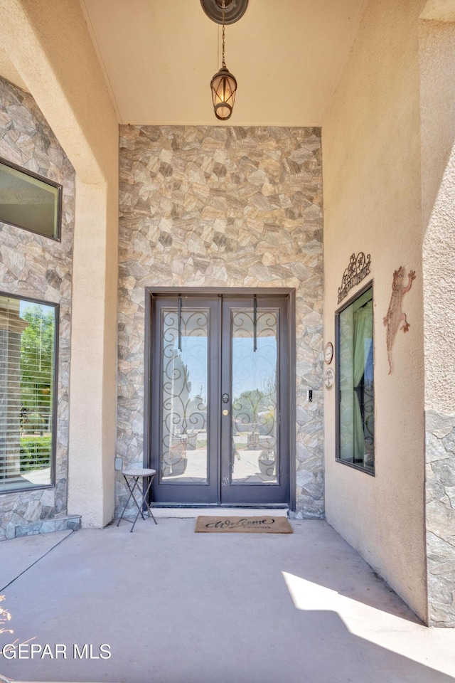 view of exterior entry with stucco siding, french doors, and stone siding