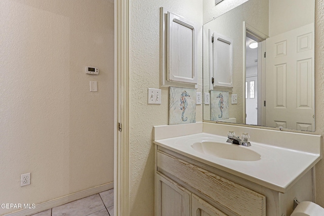 bathroom with tile patterned flooring, a textured wall, and vanity