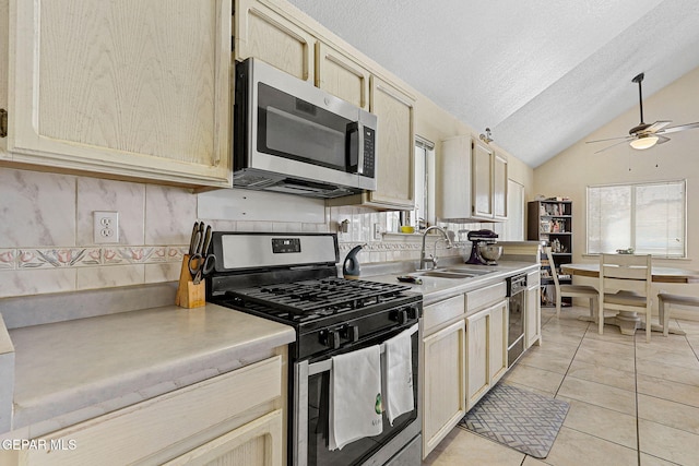 kitchen with ceiling fan, a sink, light countertops, stainless steel appliances, and tasteful backsplash