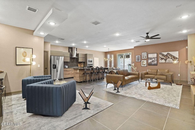 living room with baseboards, visible vents, ceiling fan with notable chandelier, and recessed lighting