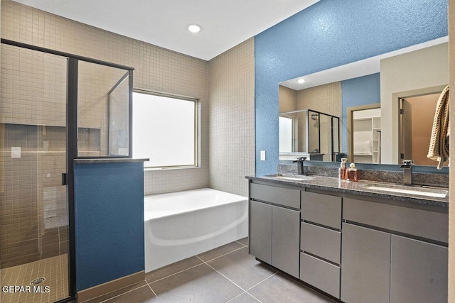bathroom featuring a bath, tile patterned flooring, a sink, and a shower stall