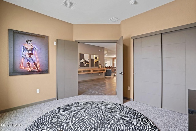carpeted bedroom with a closet, visible vents, and baseboards
