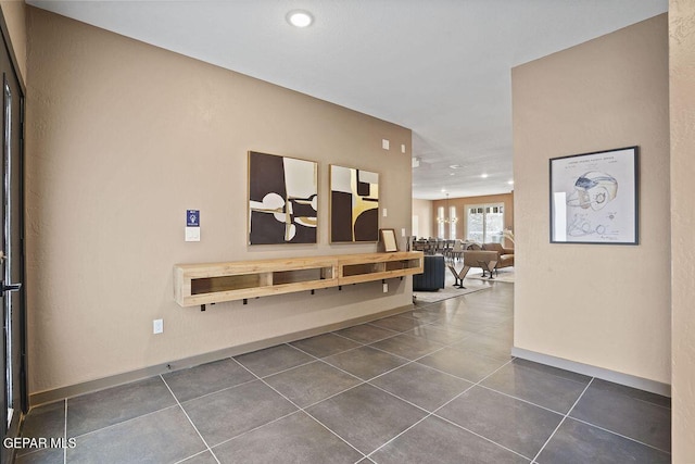 corridor with recessed lighting, dark tile patterned floors, and baseboards