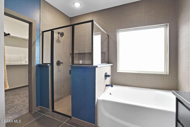 bathroom with a garden tub, tile patterned flooring, a walk in closet, and a shower stall