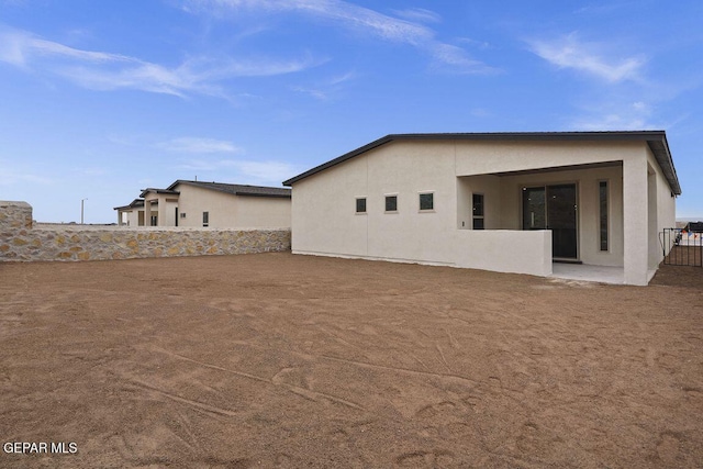 rear view of house featuring fence, stucco siding, and a patio area