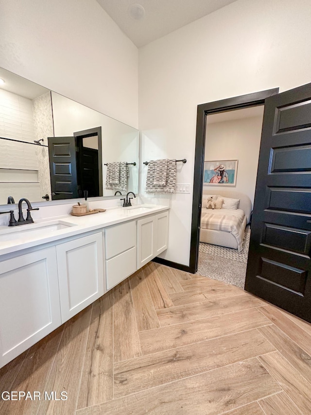 full bathroom with baseboards, connected bathroom, double vanity, and a sink