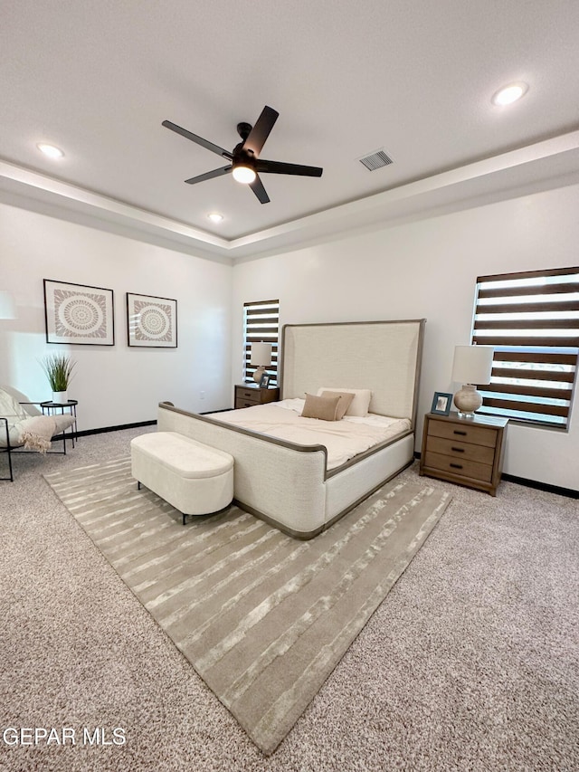 bedroom featuring recessed lighting, a tray ceiling, visible vents, baseboards, and carpet floors