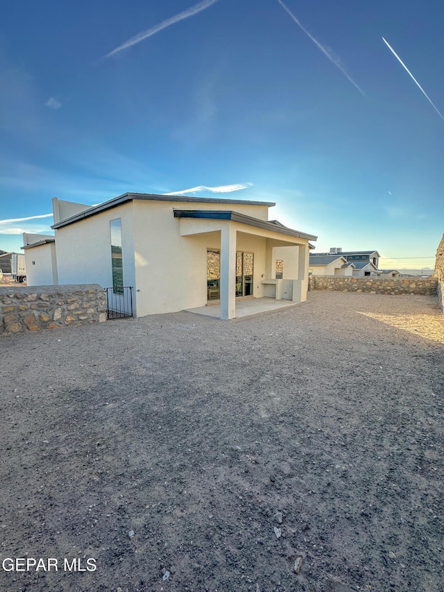 rear view of property featuring a patio and stucco siding