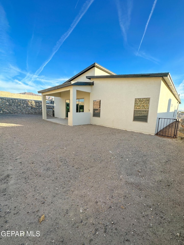 back of house with fence, stucco siding, and a patio area