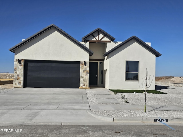 view of front of property with stone siding, stucco siding, driveway, and an attached garage