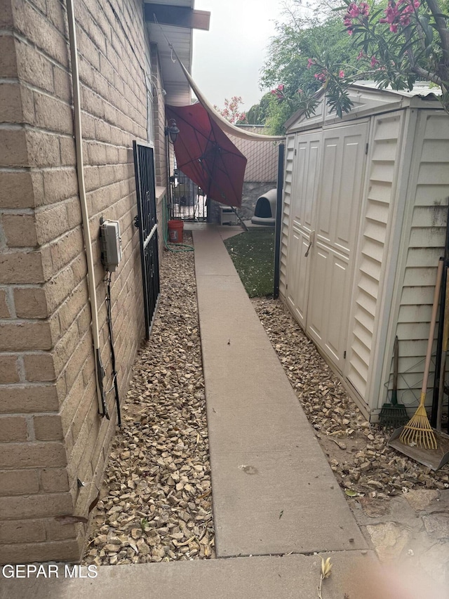 view of home's exterior featuring a storage shed, a gate, an outdoor structure, and fence