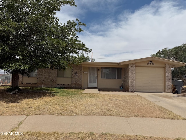 ranch-style home with an attached garage, brick siding, concrete driveway, and a front yard