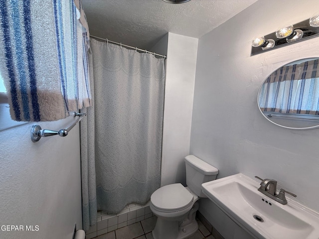 bathroom featuring a sink, a textured ceiling, tile patterned flooring, a shower with shower curtain, and toilet