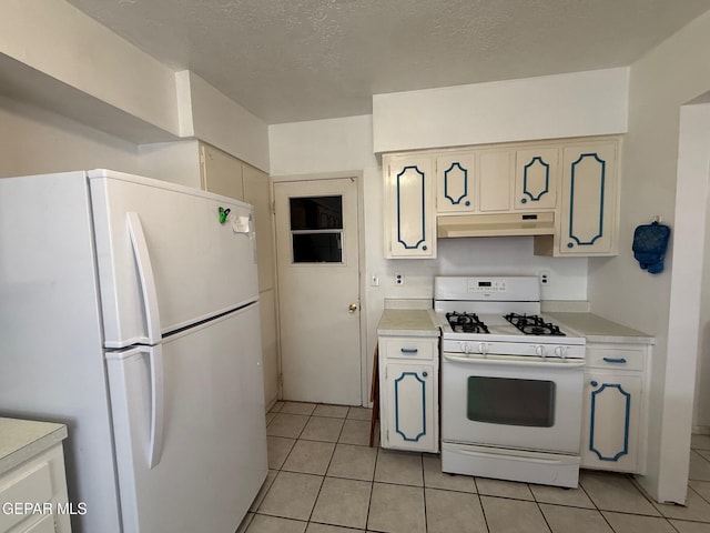 kitchen featuring white appliances, under cabinet range hood, light countertops, light tile patterned flooring, and a textured ceiling