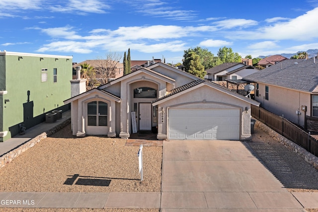 view of front of house featuring an attached garage, stucco siding, concrete driveway, fence, and central AC