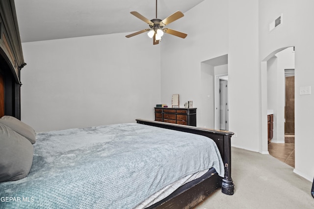 carpeted bedroom with high vaulted ceiling, arched walkways, ceiling fan, and baseboards