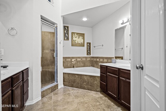 bathroom featuring two vanities, a stall shower, and a bath
