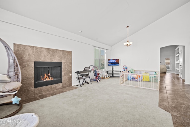 recreation room featuring a tile fireplace, high vaulted ceiling, tile patterned floors, arched walkways, and a chandelier
