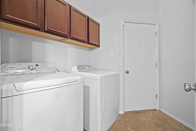 washroom featuring washer and clothes dryer, cabinet space, and baseboards