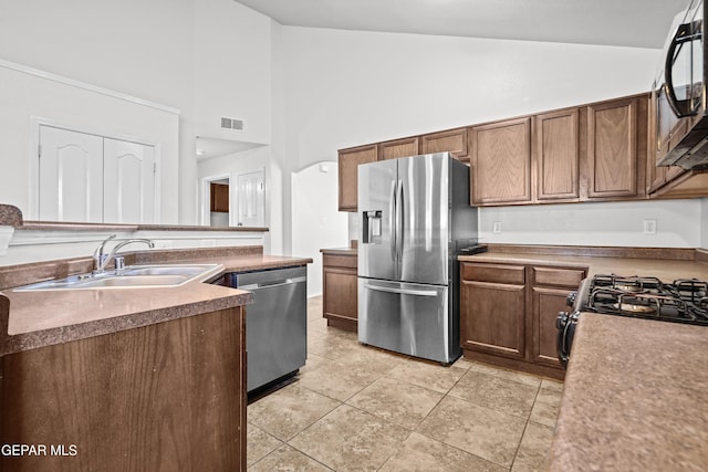 kitchen featuring stainless steel appliances, a sink, high vaulted ceiling, and light tile patterned floors