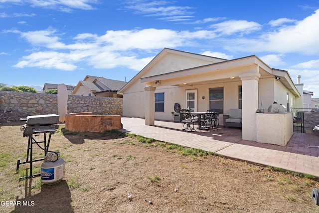 rear view of house with a patio, fence, and stucco siding