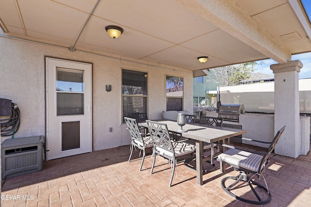 view of patio featuring outdoor dining space, area for grilling, and heating unit