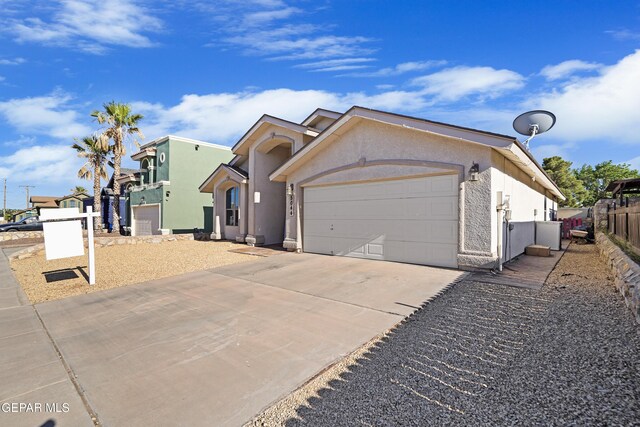 view of front of house featuring driveway, an attached garage, stucco siding, and fence