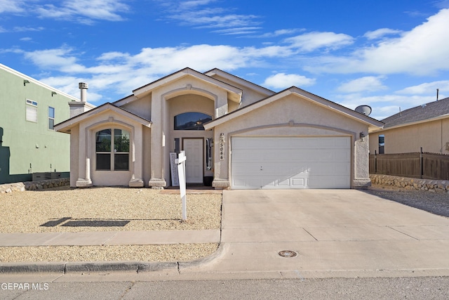view of front of house featuring concrete driveway, stucco siding, an attached garage, and fence