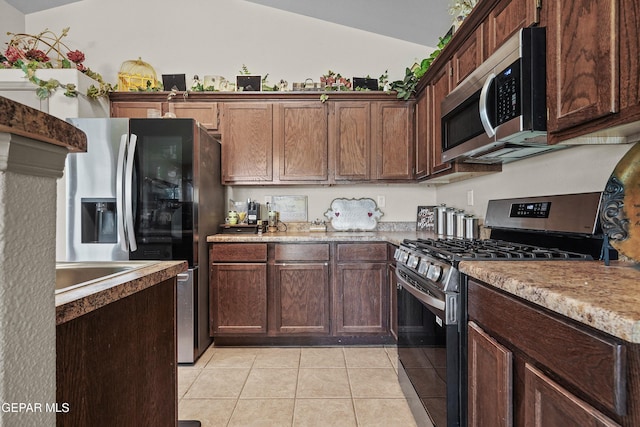 kitchen featuring lofted ceiling, stainless steel appliances, light tile patterned flooring, and light countertops