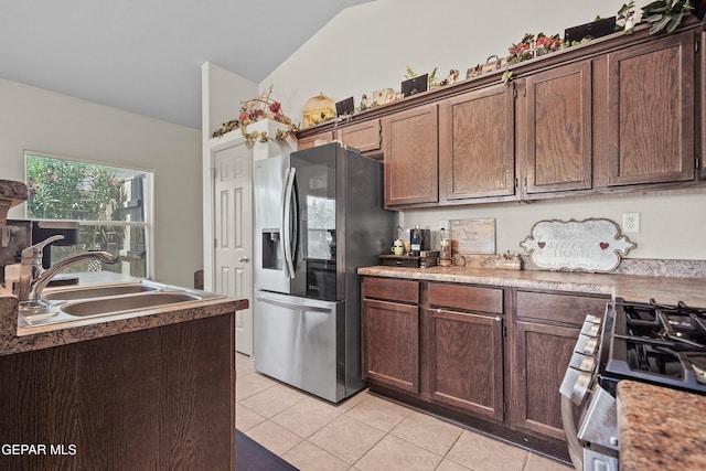 kitchen featuring a sink, vaulted ceiling, light tile patterned floors, and appliances with stainless steel finishes