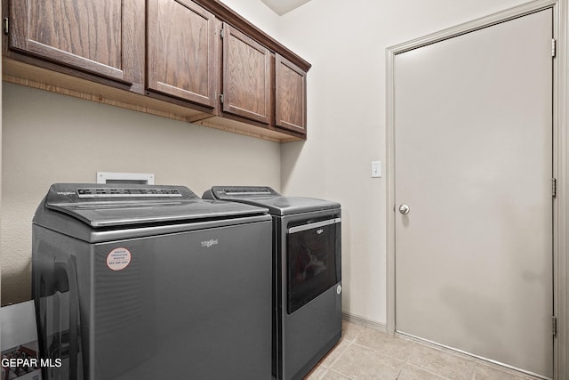 laundry area with independent washer and dryer, light tile patterned flooring, and cabinet space