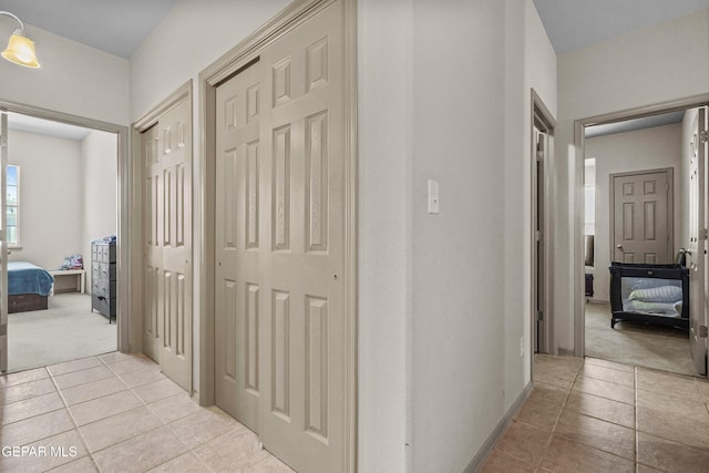 hallway with light tile patterned floors and light colored carpet
