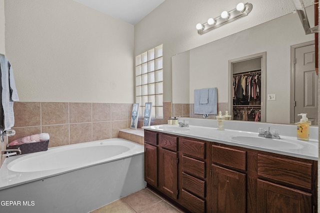 full bathroom with a sink, double vanity, a bath, and tile patterned floors