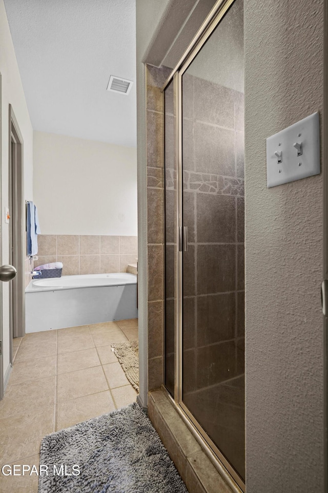 bathroom featuring a stall shower, tile patterned floors, tile walls, visible vents, and a bath