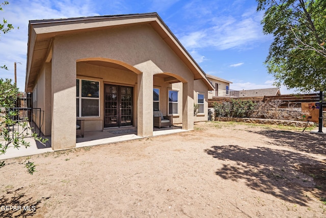rear view of property featuring fence, stucco siding, and a patio area